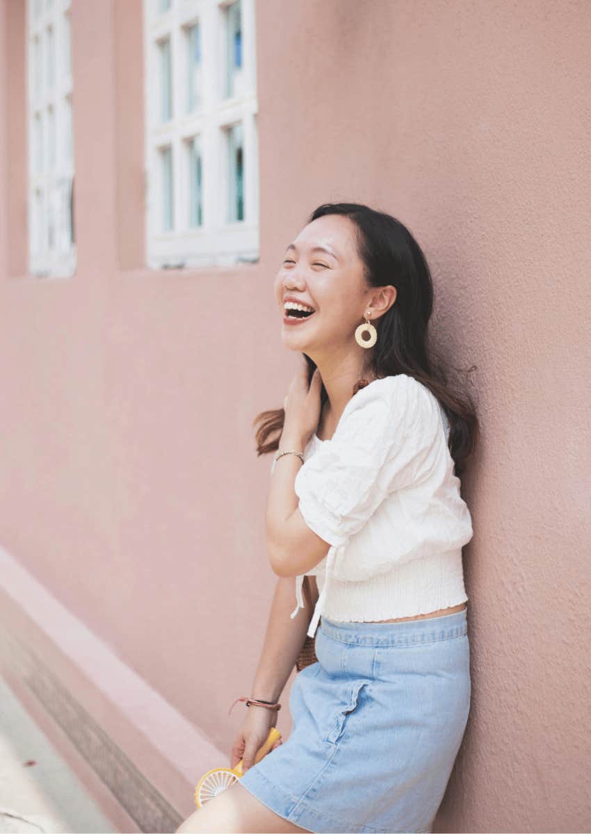 joyful young woman leaning against a wall