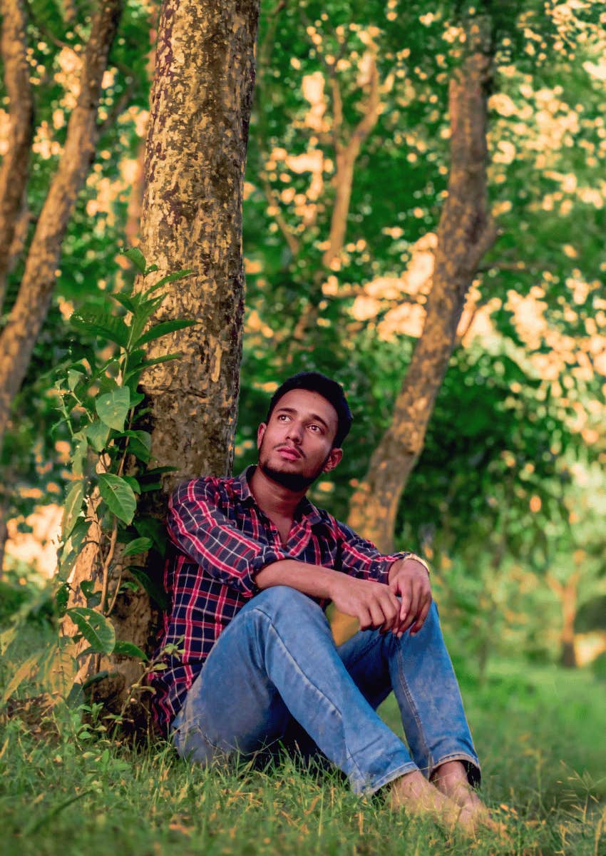 man sitting against a tree with a peaceful expression