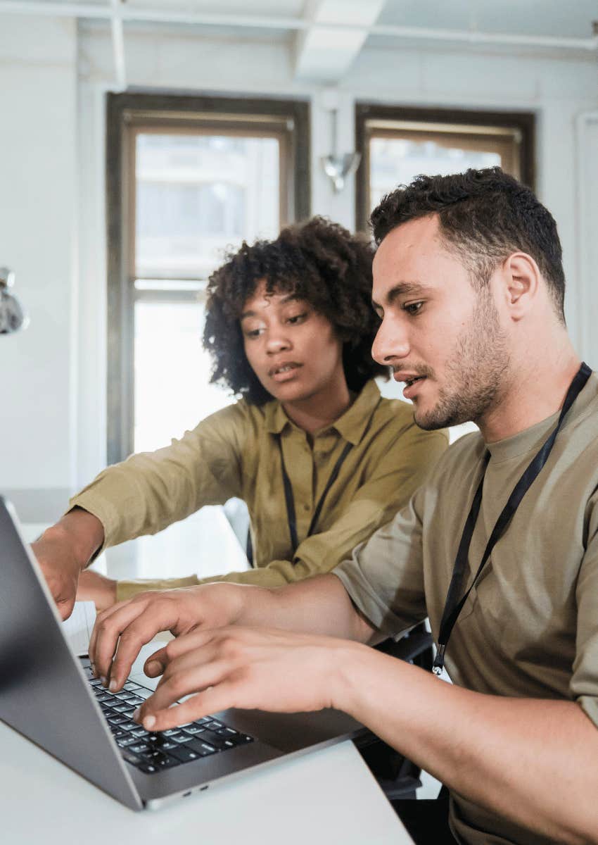 mentor helping mentee on laptop