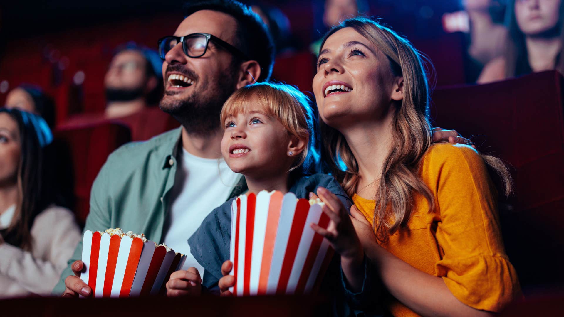 parents and child at the movies eating popcorn