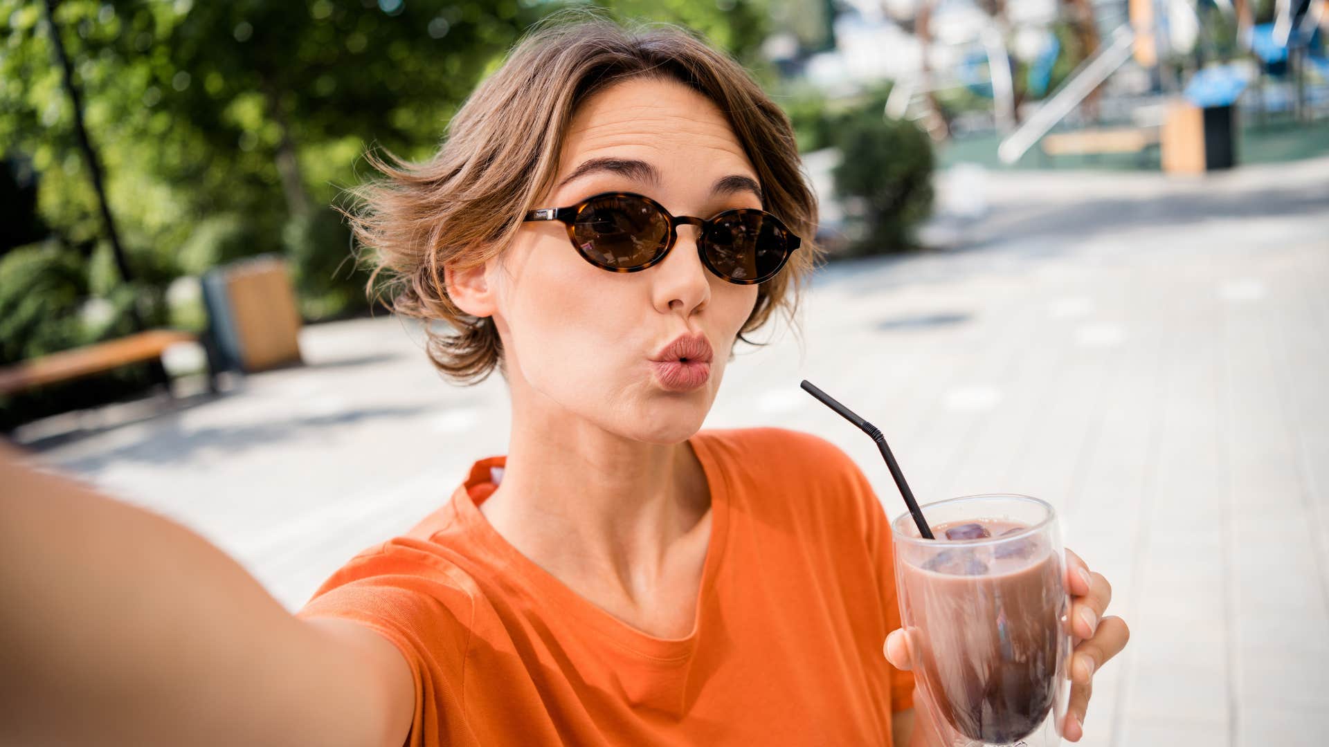 Silly millennial takes selfie with coffee showing source of stress