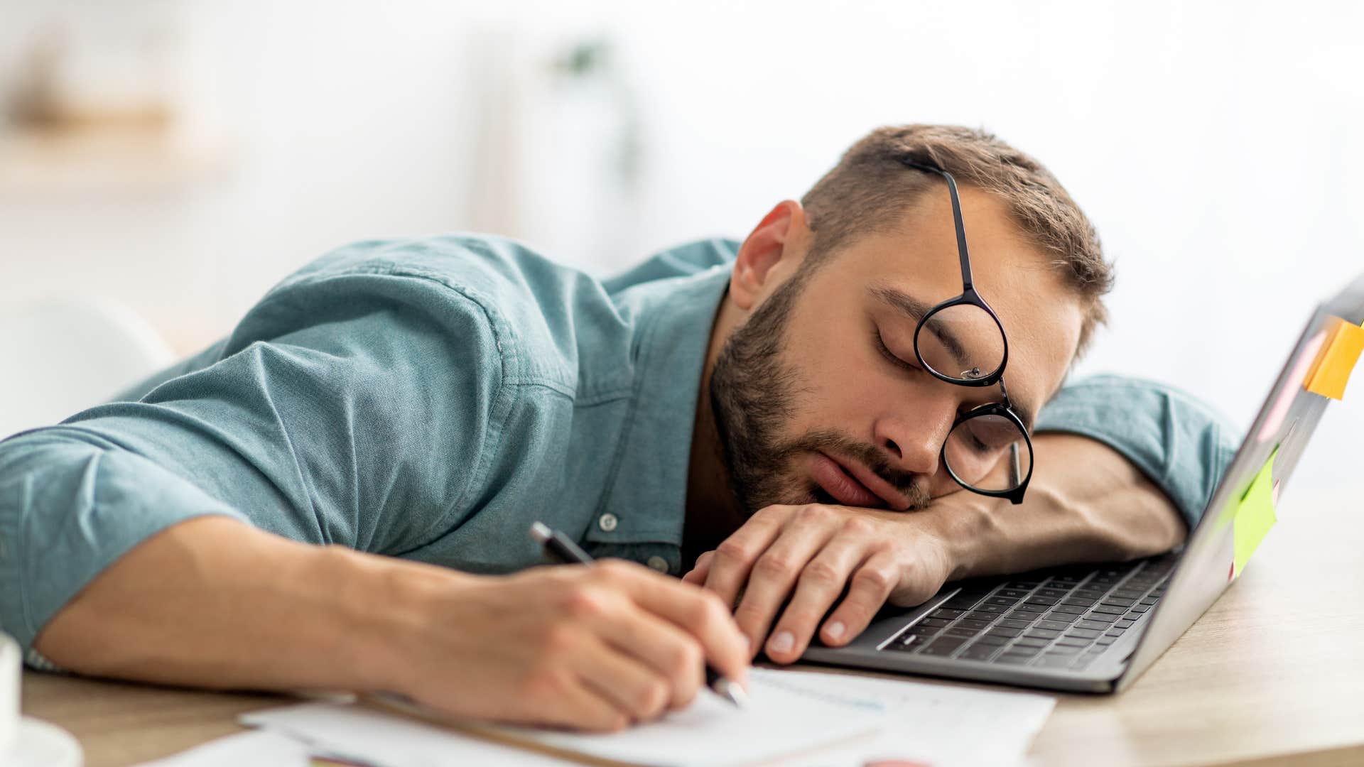 Tired millennial sleeps on desk showing stress and struggle