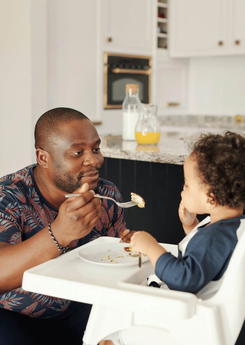 parent feeding child while in a high chair