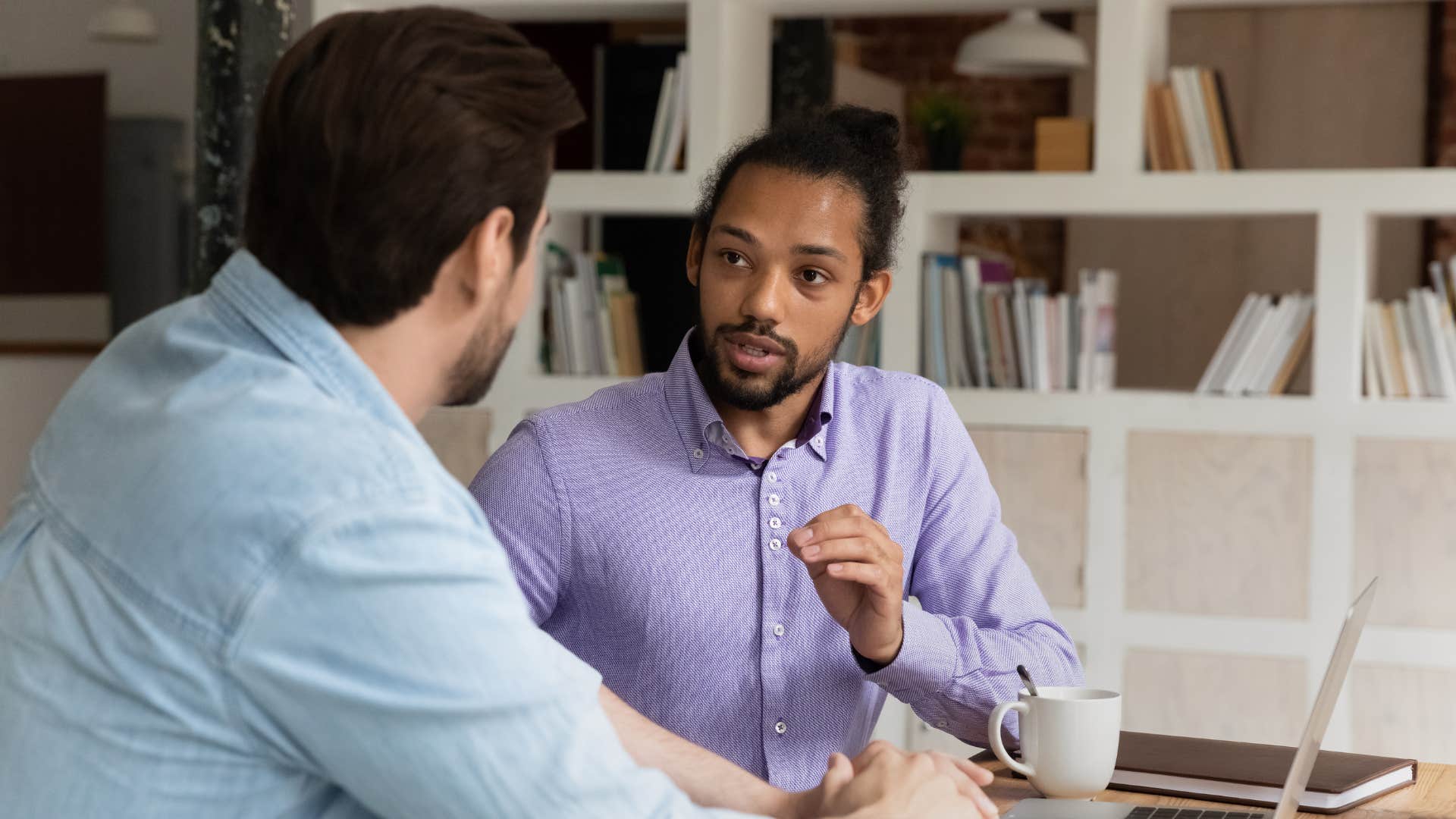 man in purple shirt telling coworker let's pause there for a second