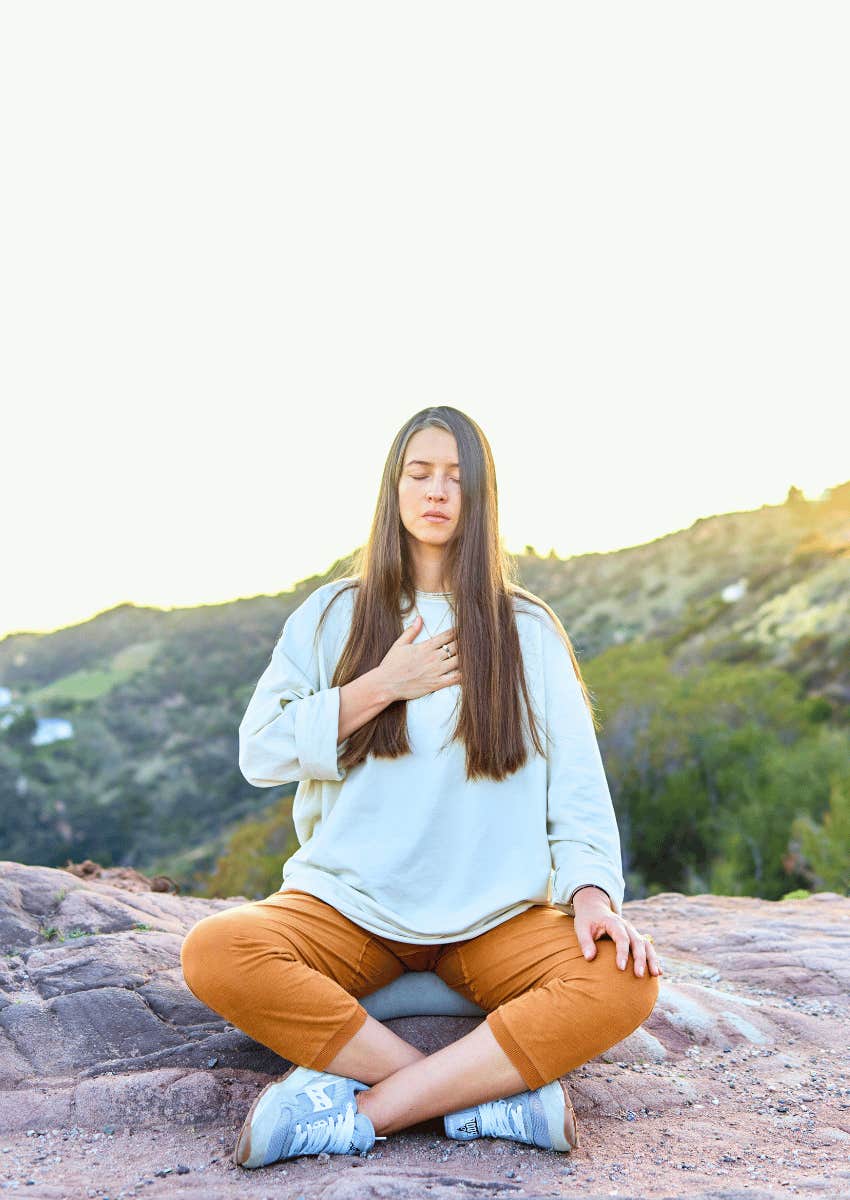 peaceful young woman meditating outdoors