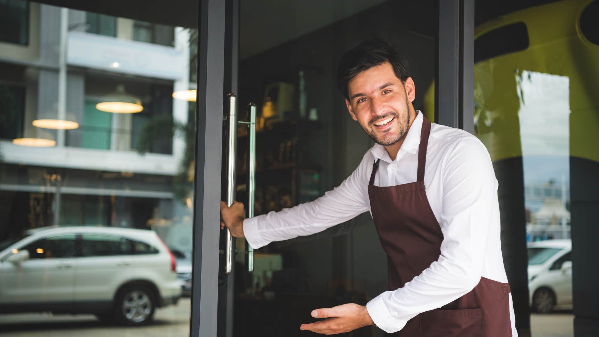 cooperative man smiling and holding the front door open