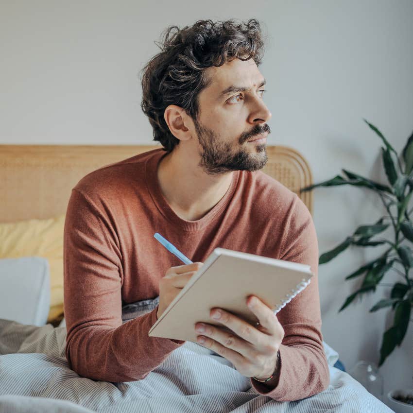 man recording his speaking in a journal in bed