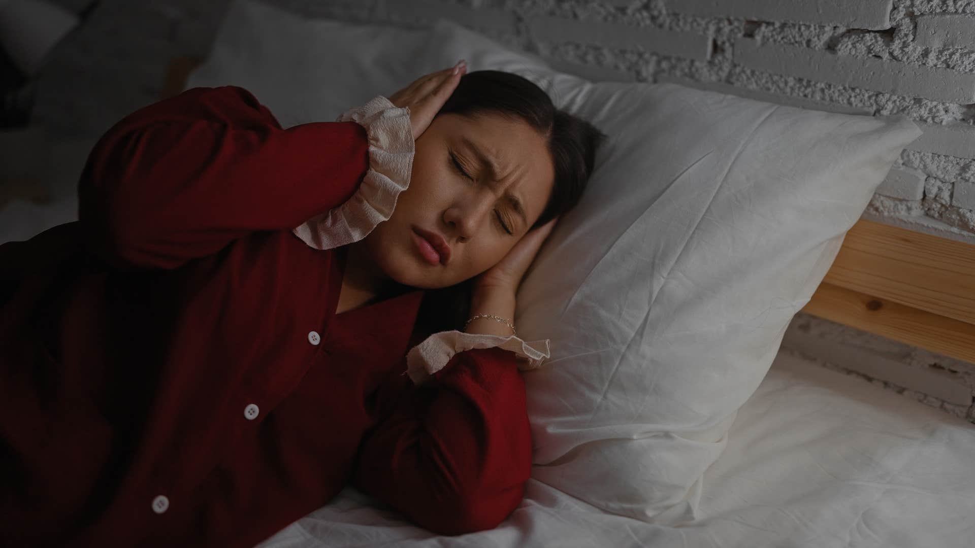 woman in red sensitive to overstimulation as she covers ears