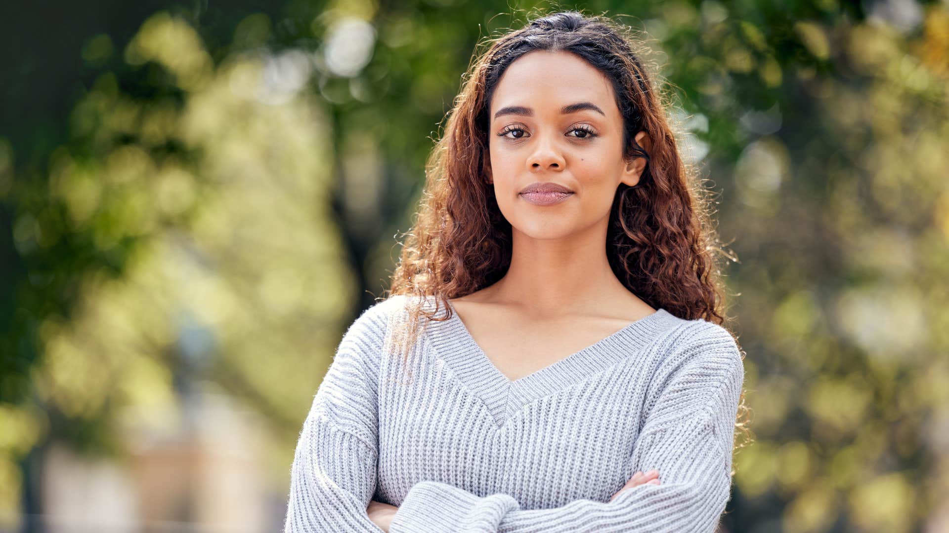 woman in gray shirt crossing arms as she's confident