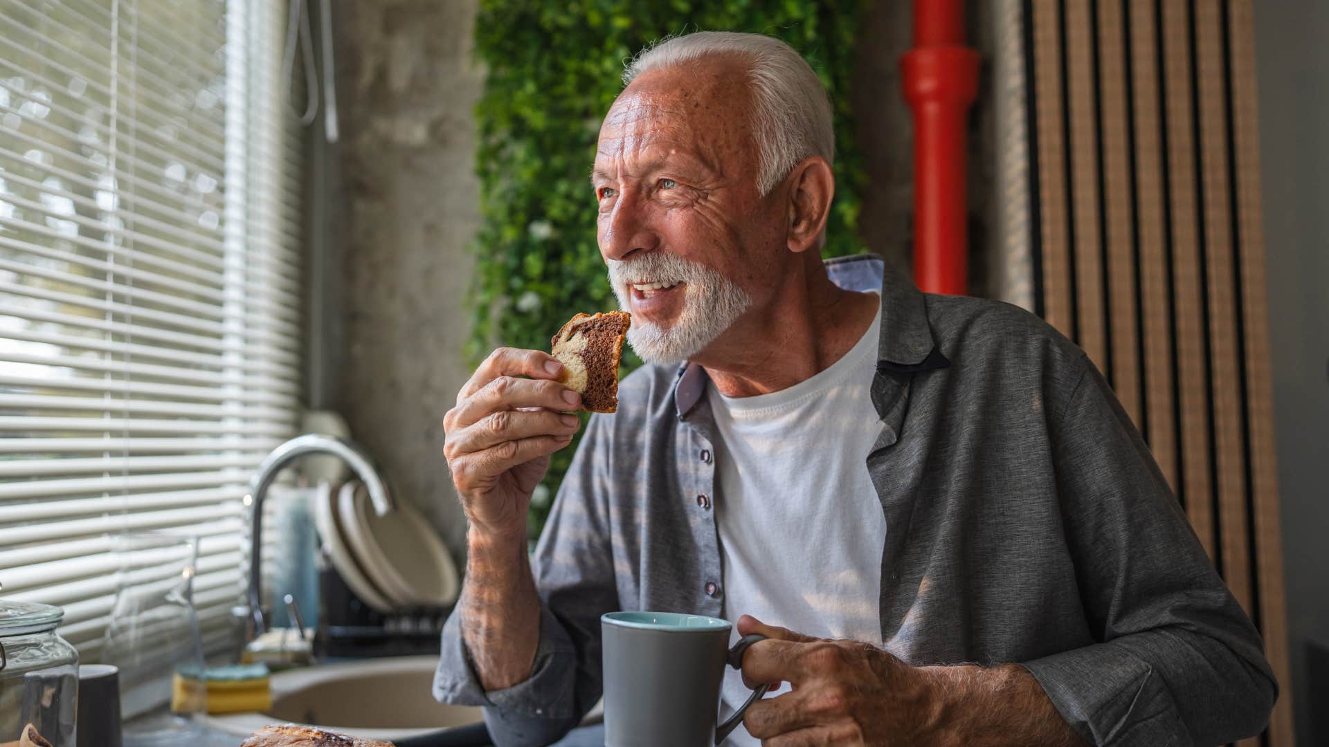 introverted man sipping coffee with food as he looks out window