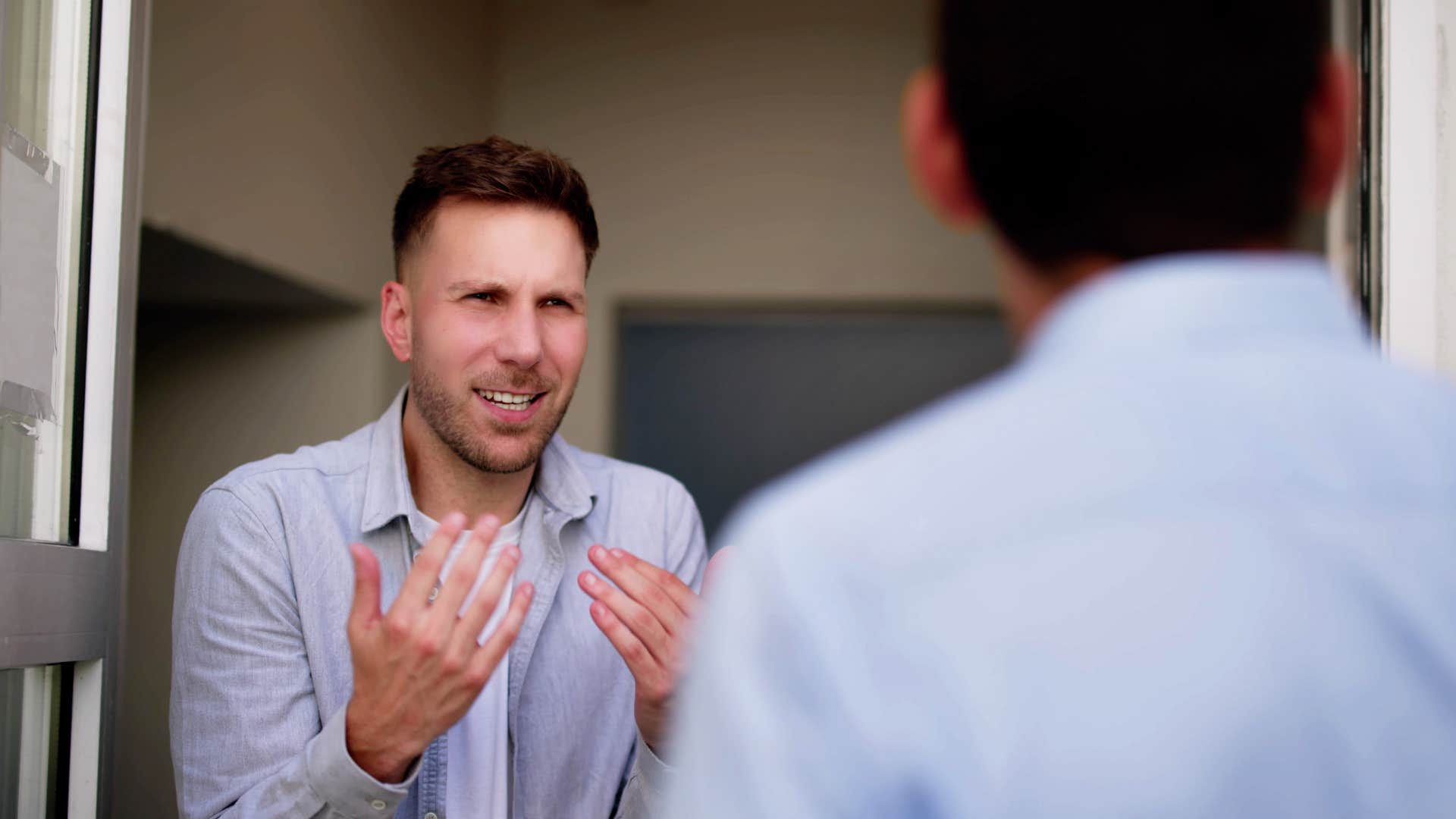 man arguing with friend at front door