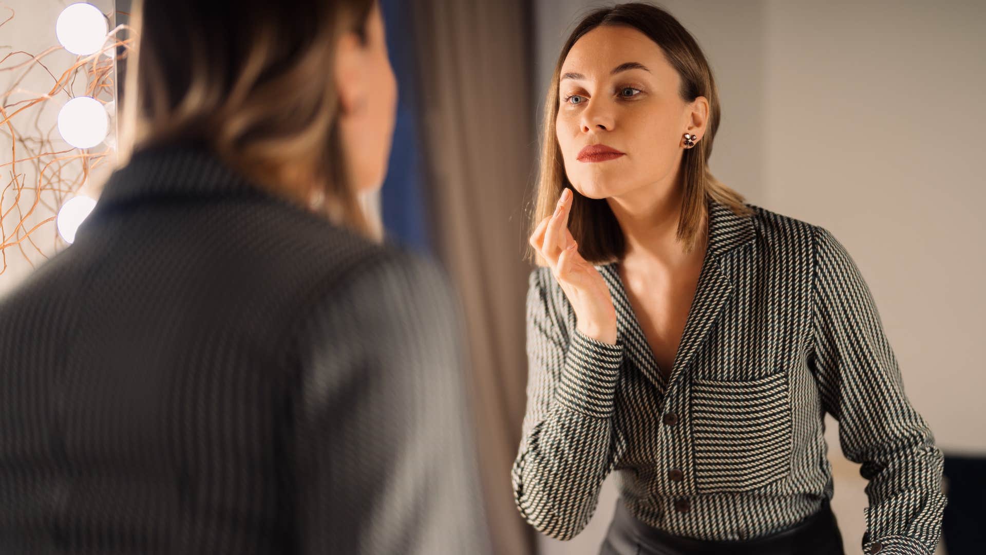 woman who doesn't follow or chase after trends looking in a mirror