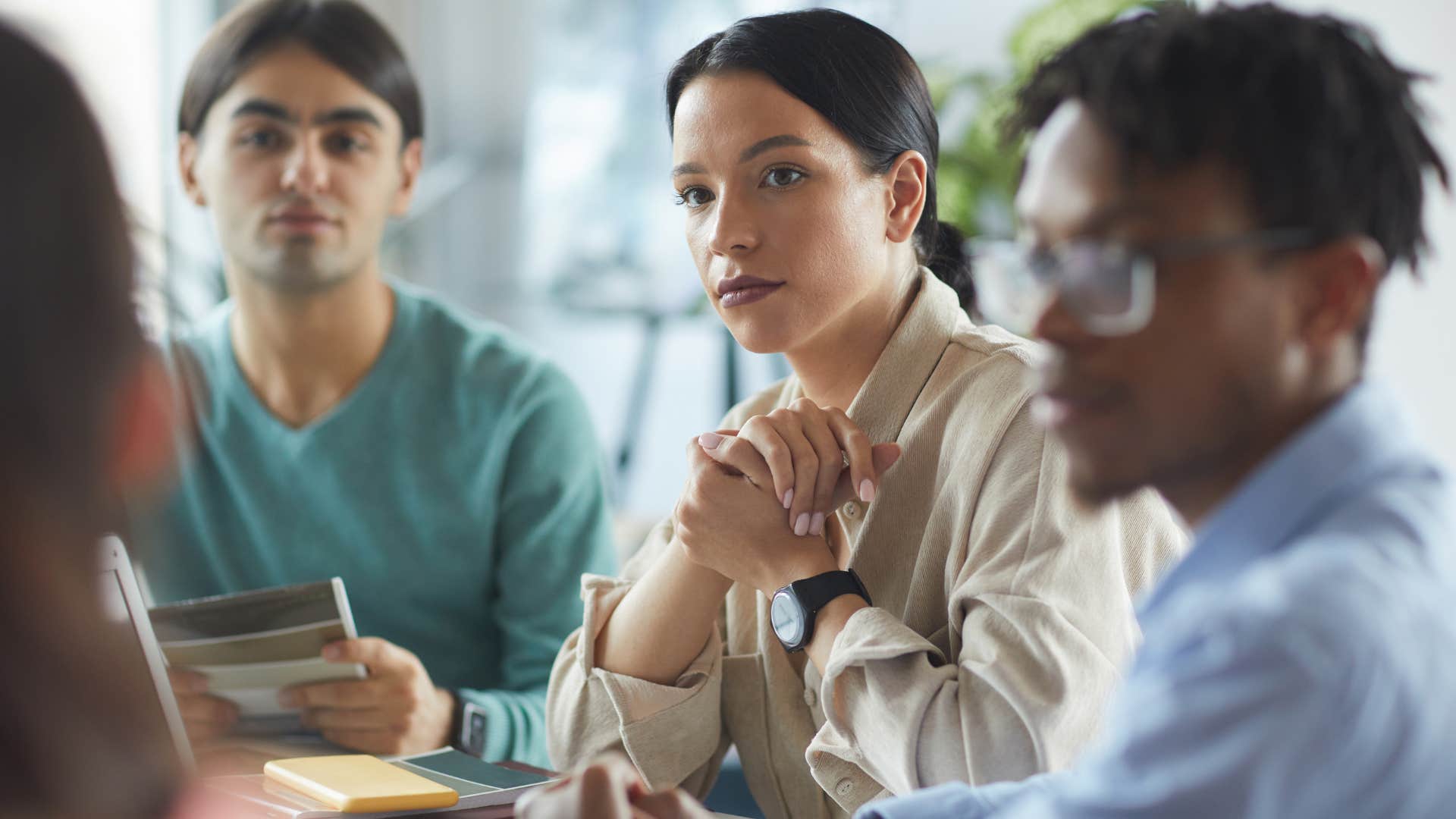 serious woman sitting in group discussion that lacks collaboration