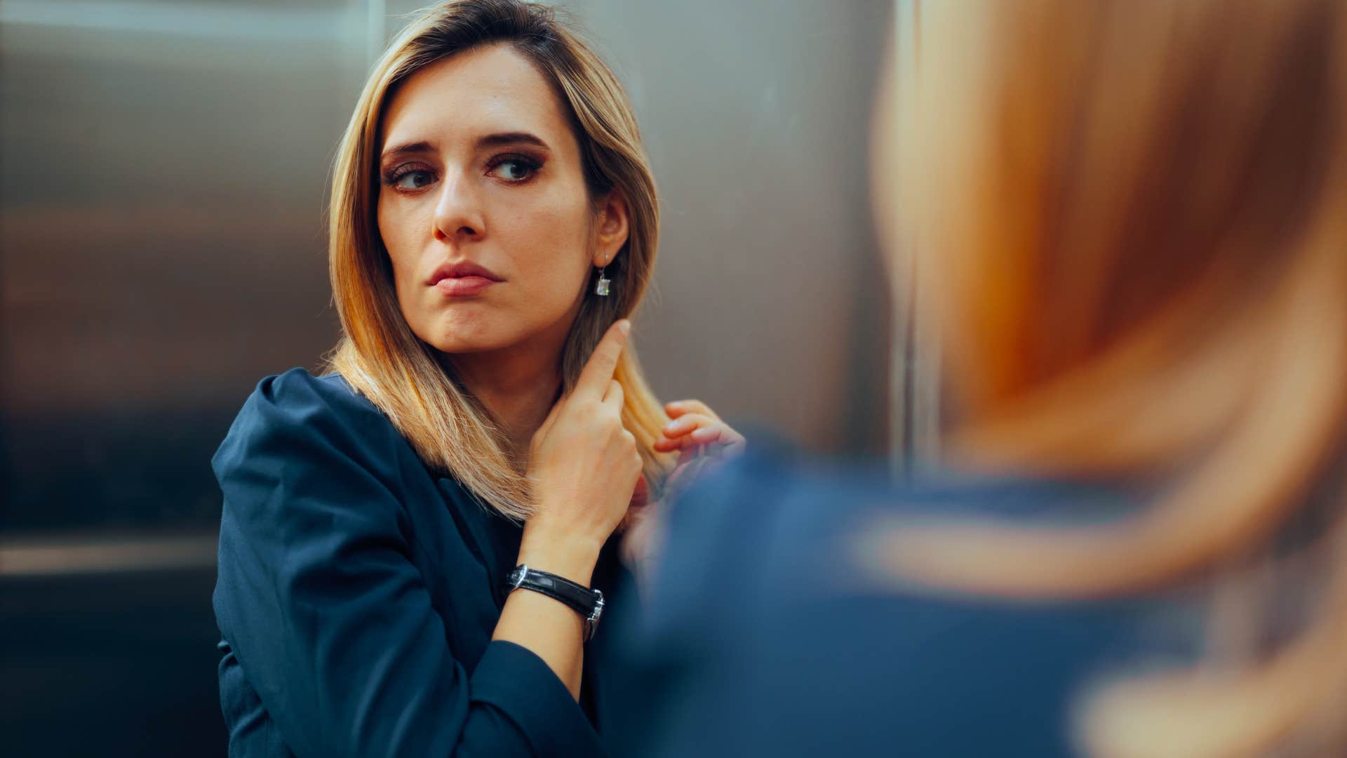 woman who's a perfectionist doing her hair in a mirror