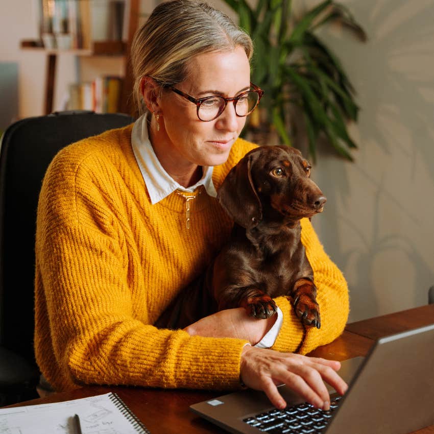 introverted woman working at home with her dog in her lap
