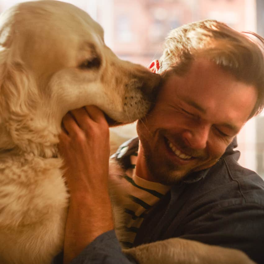 intuitive man smiling and playing with his dog