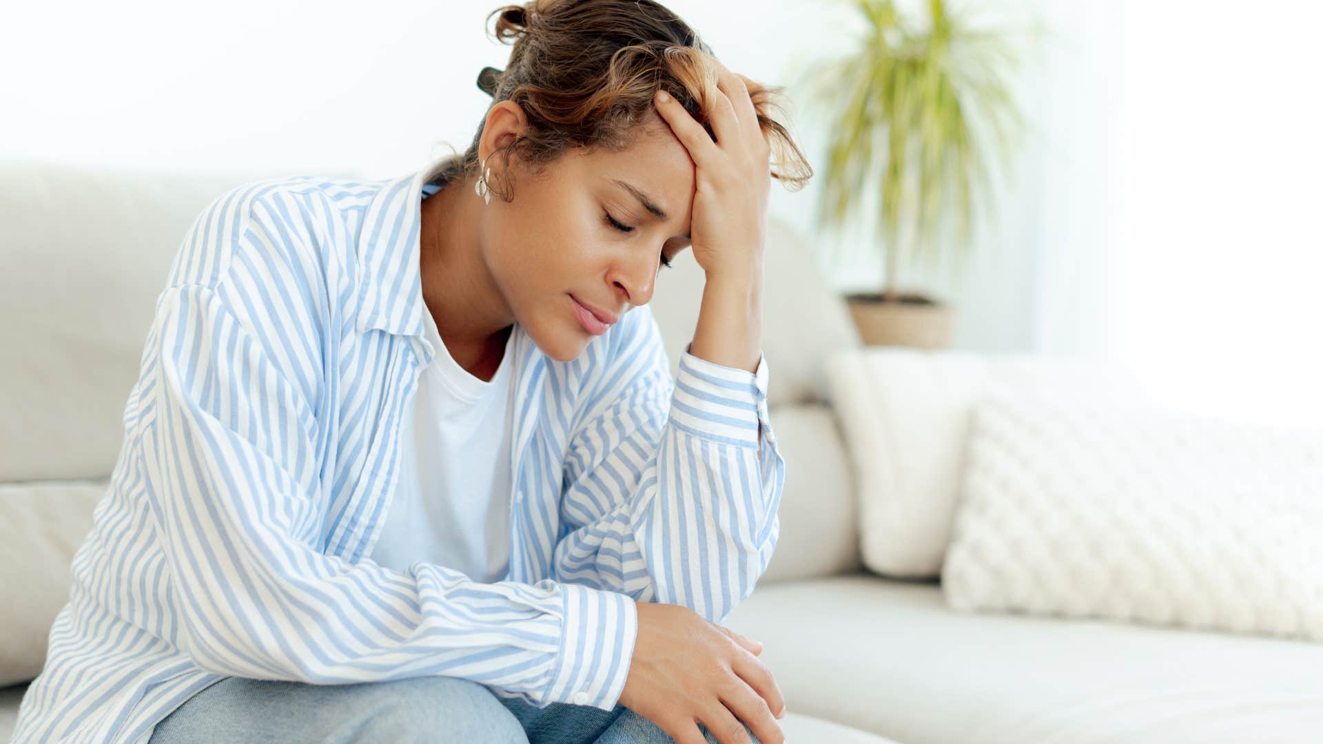exhausted woman sitting on couch at home