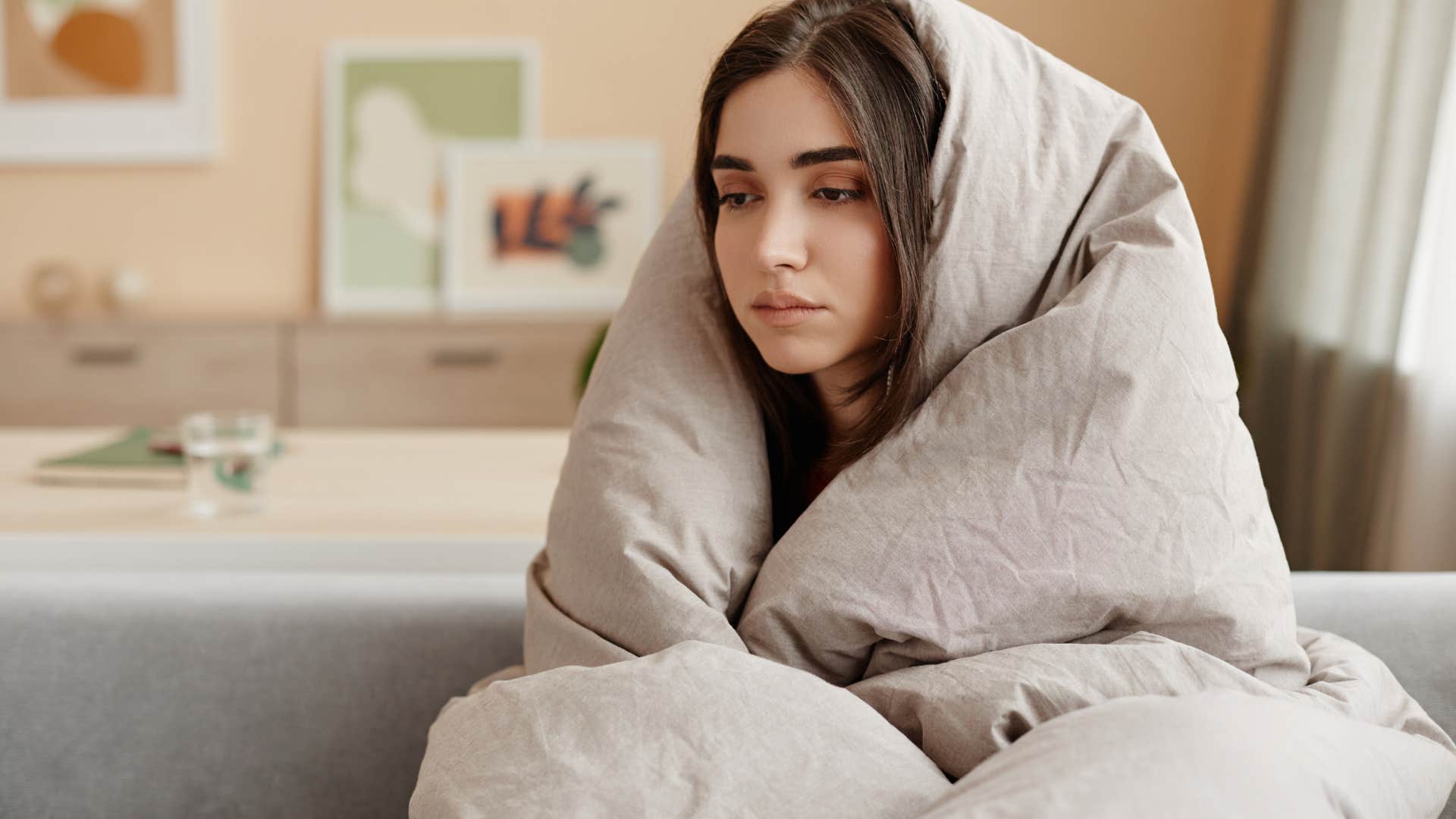 sad upset woman wrapped up in blanket not wanting to ask for help