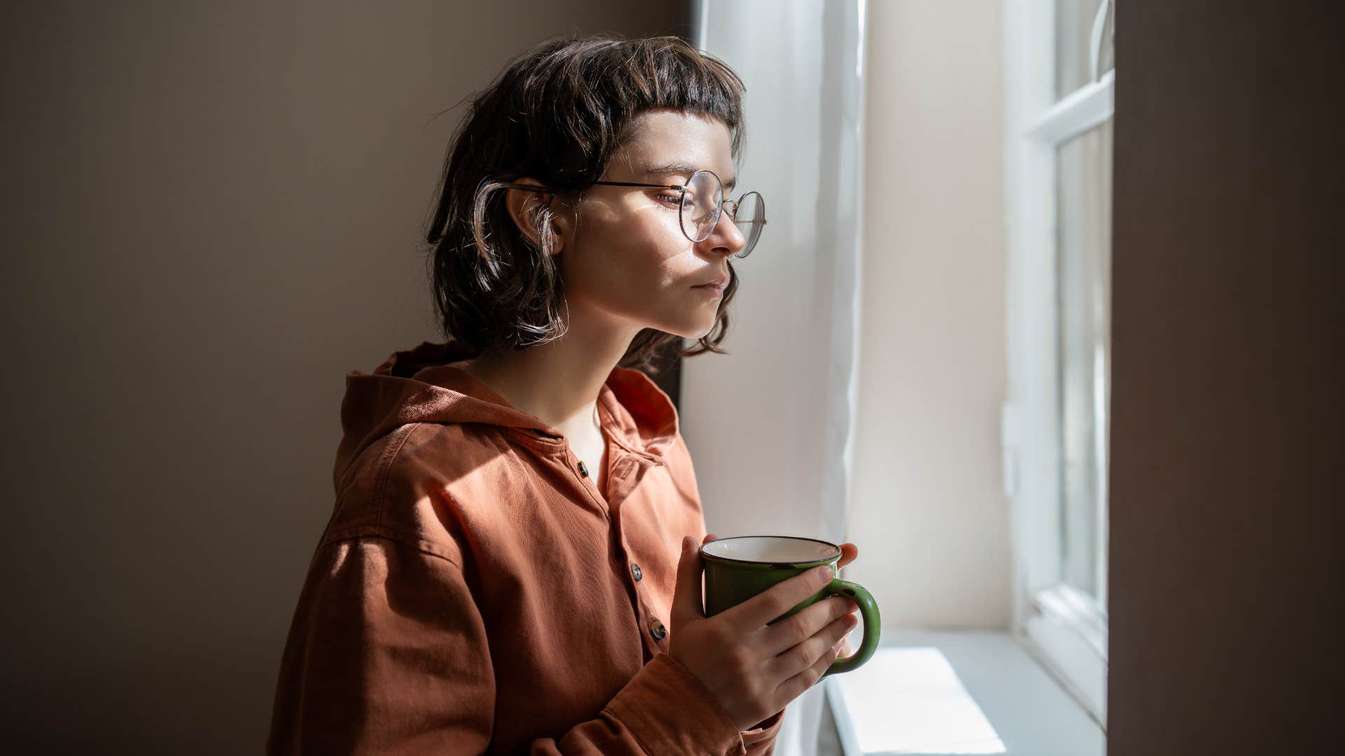 woman standing next to window at home
