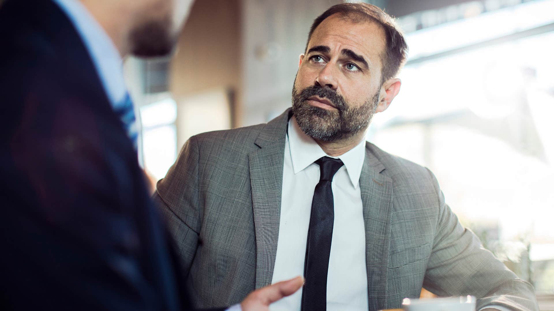 Man saying "no offense, but..." to a co-worker in an office.