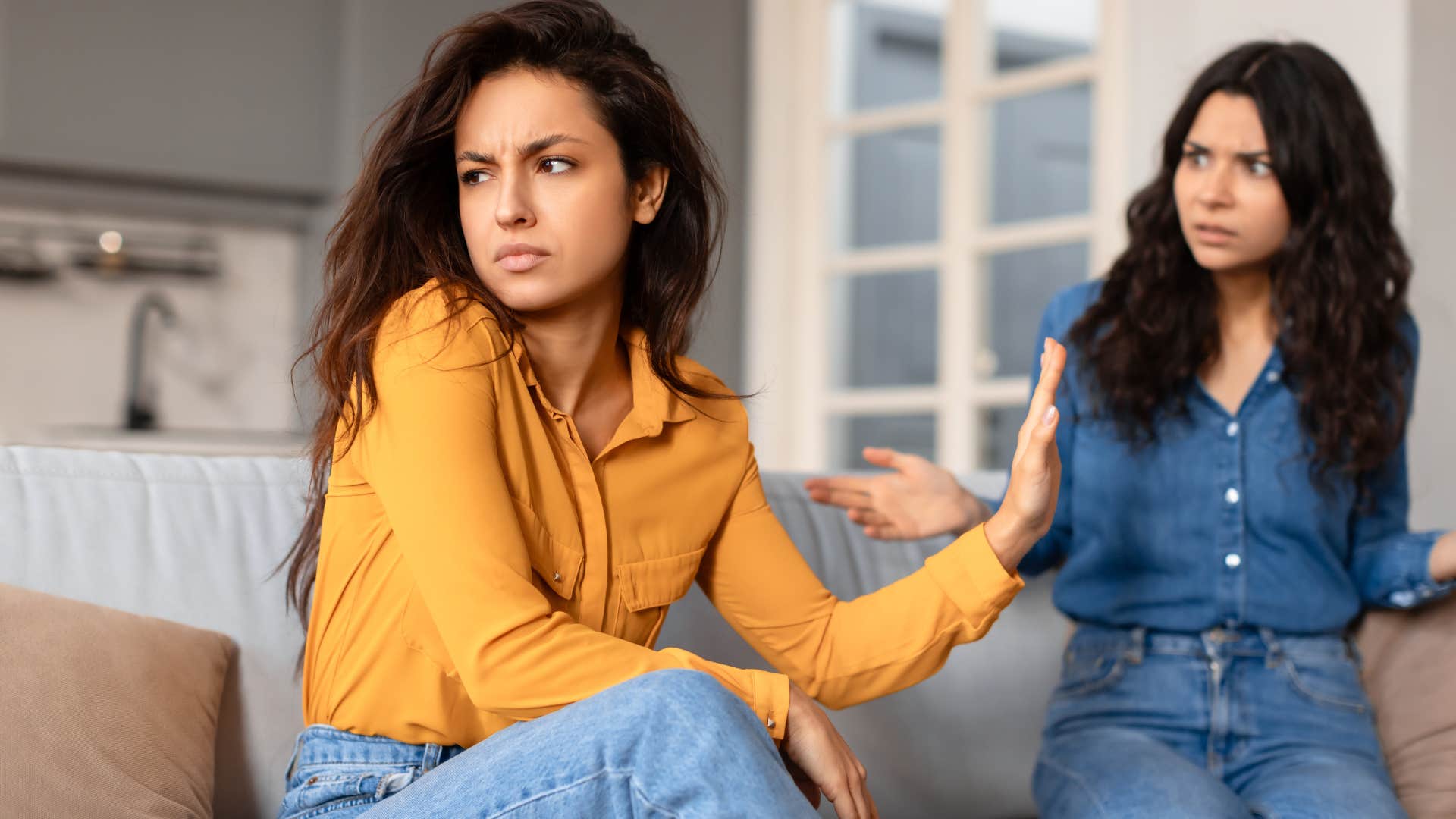 woman putting her hand up to friend saying you're just jealous