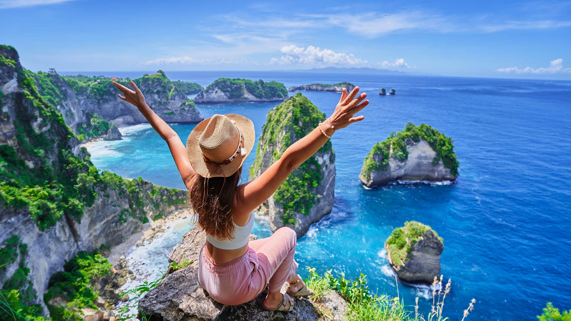 Excited woman on cliff over ocean showing get away after breakup