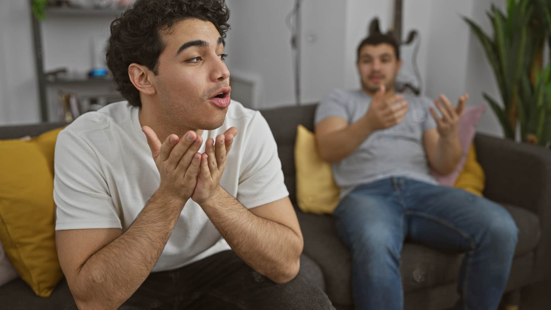 two men having debate while sitting on couch at home