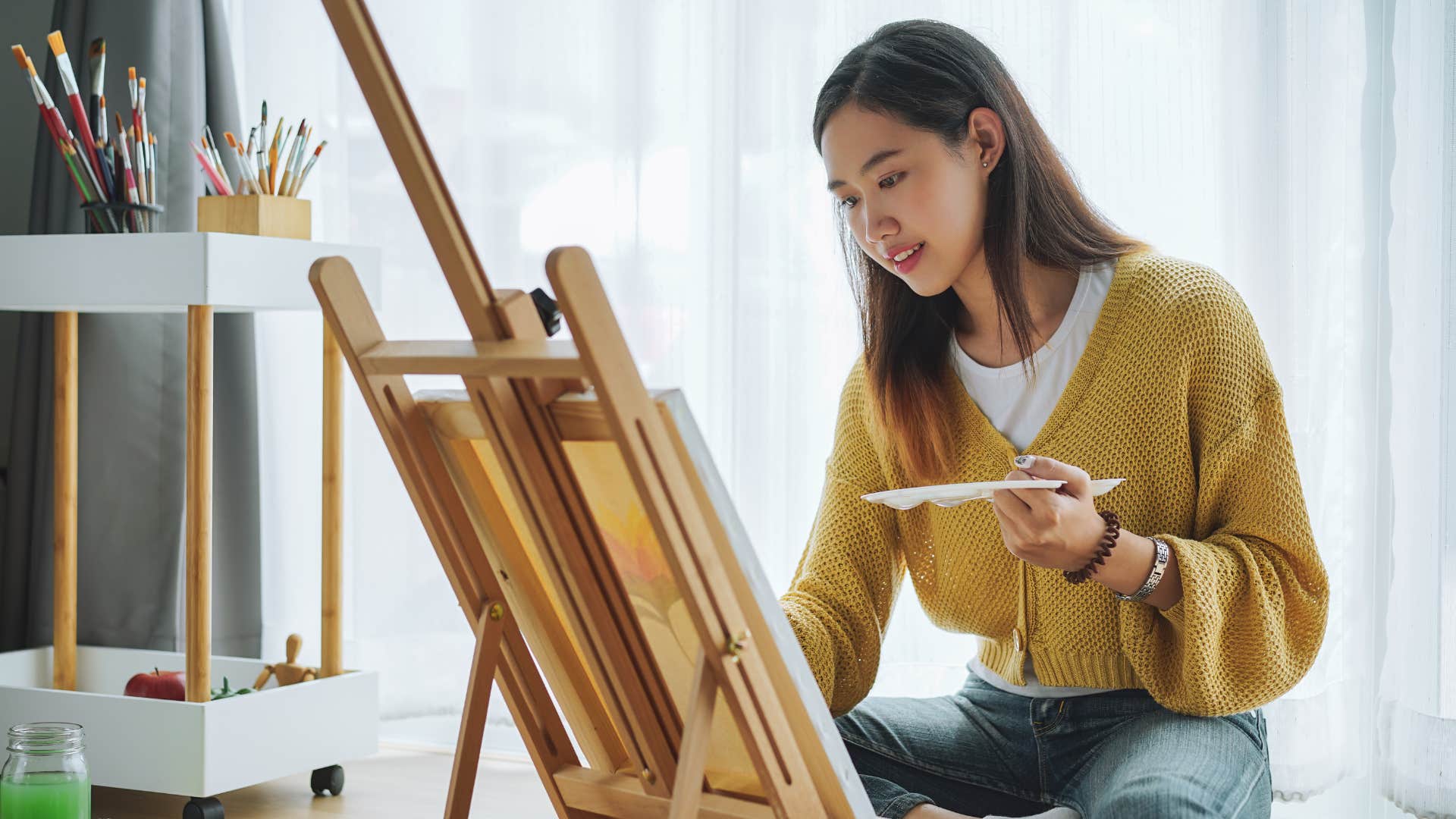 creative woman who needs noise to focus painting on canvas