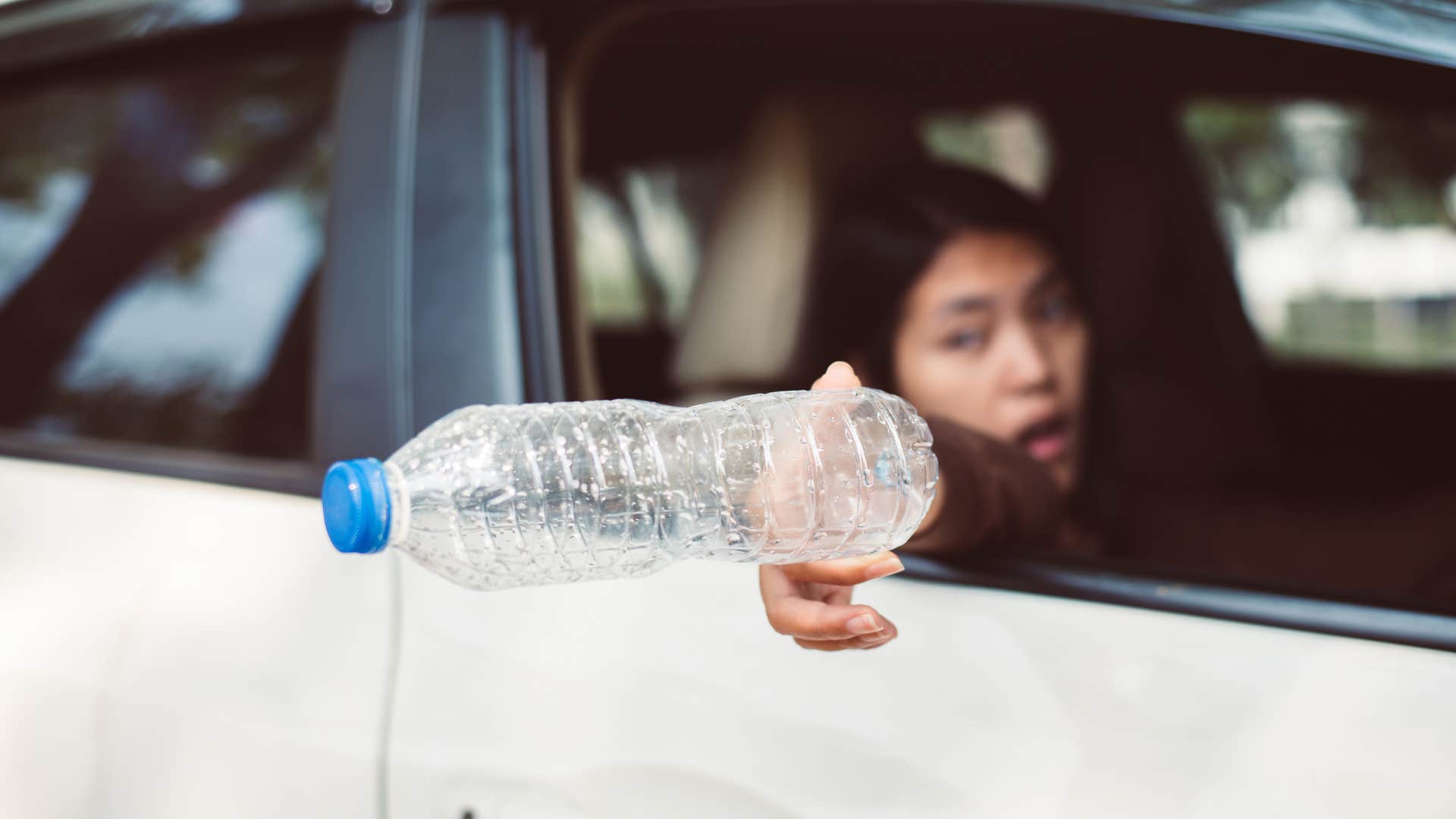 woman without common sense littering throwing trash out car