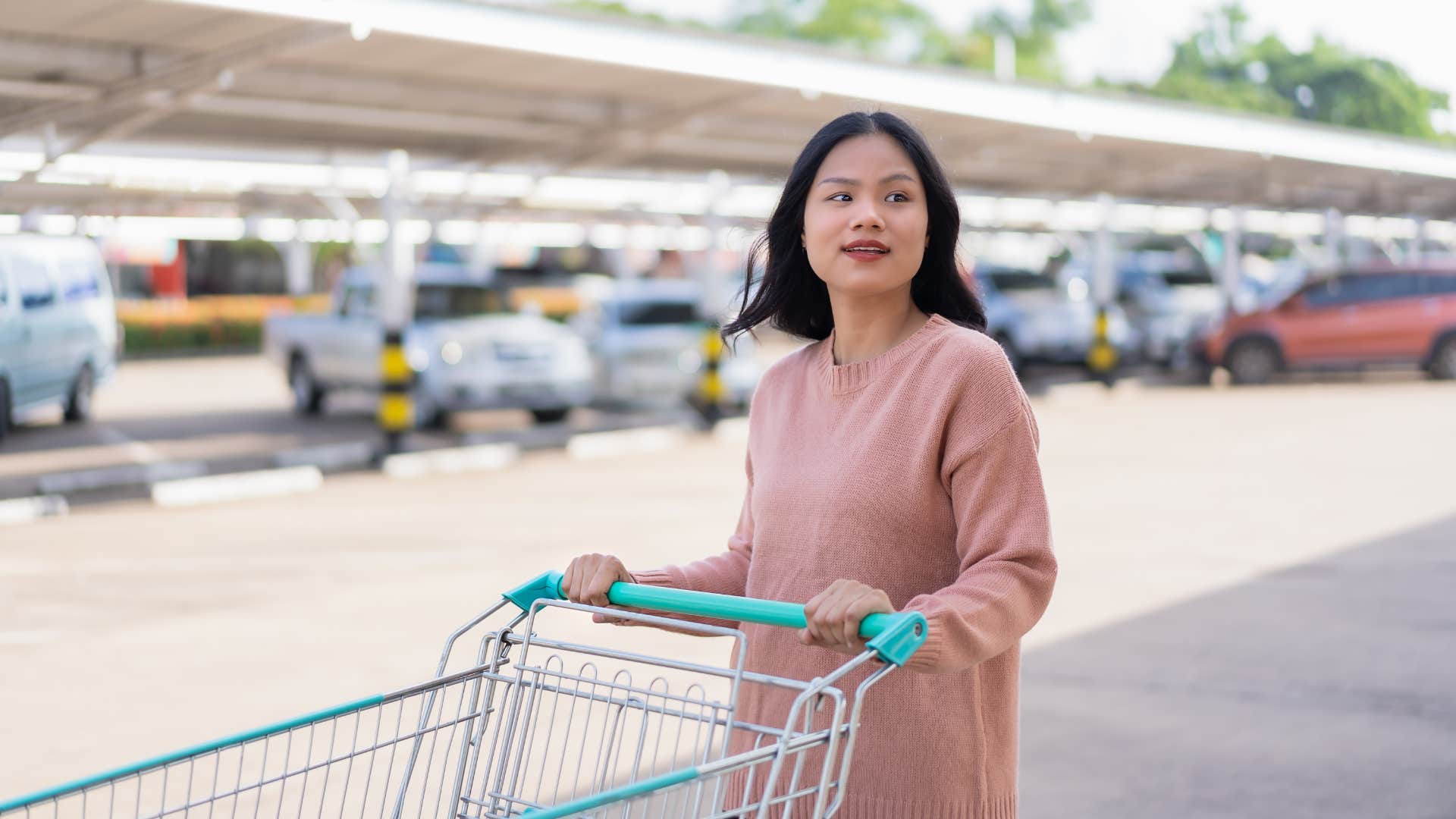 woman thinking about returning shopping cart in parking lot