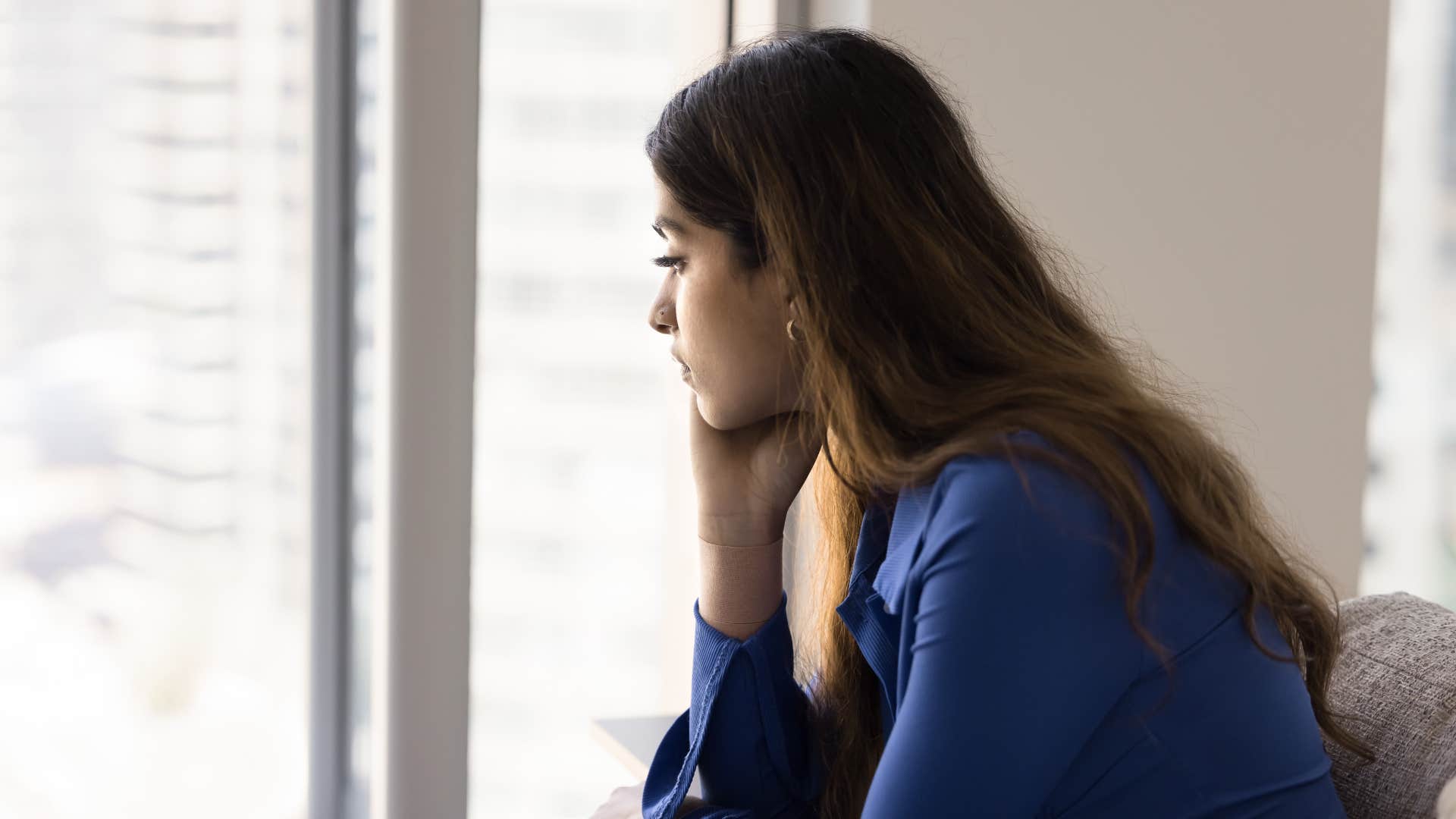 lonely woman looking ou window thinking i don't really talk to anyone about that