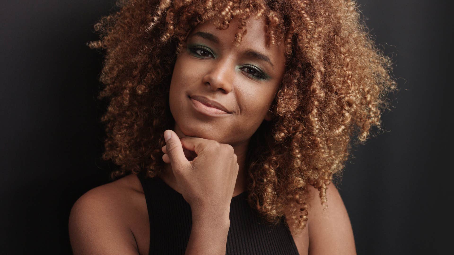 Confident woman rests chin on fist showing belief to attract men