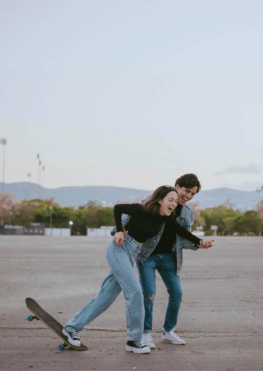playful couple playing on skateboard