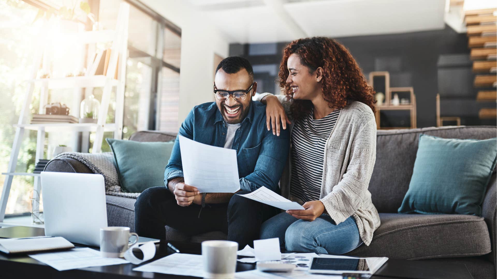 Laughing couple with paperwork learn together showing way to be happier in marriage