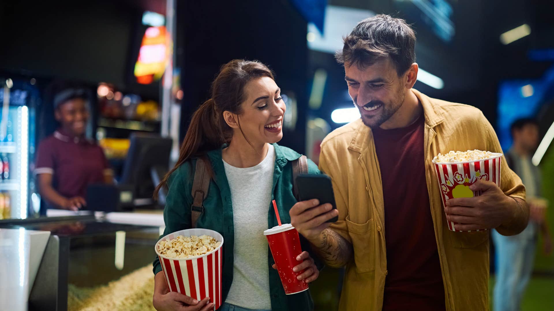 excited couple with popcorn check movie schedule together showing way to be happier in marriage