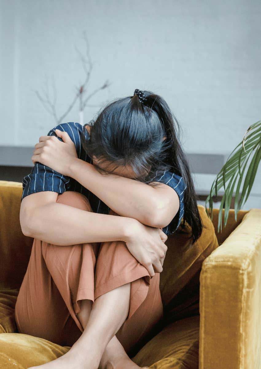 sad and grieving woman hugging her knees to her chest