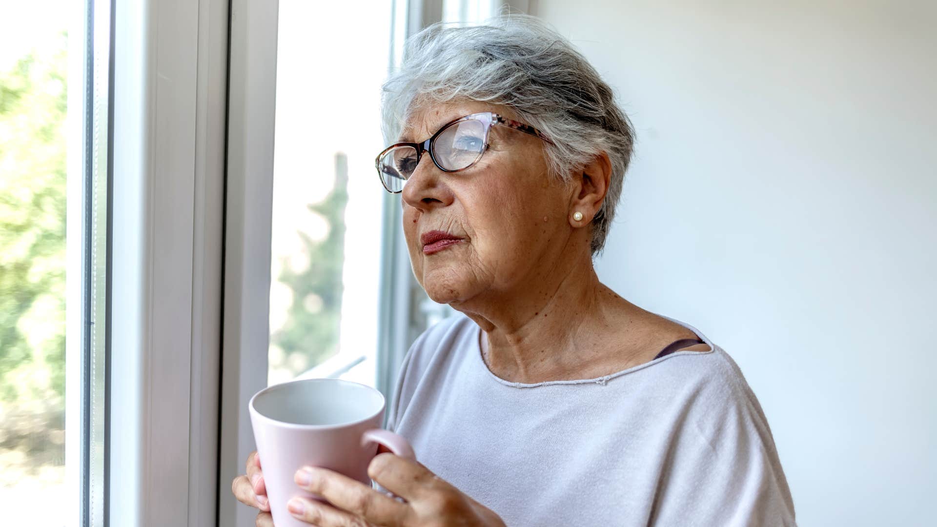 Introspective person looks out window showing happiness challenges negative thinking