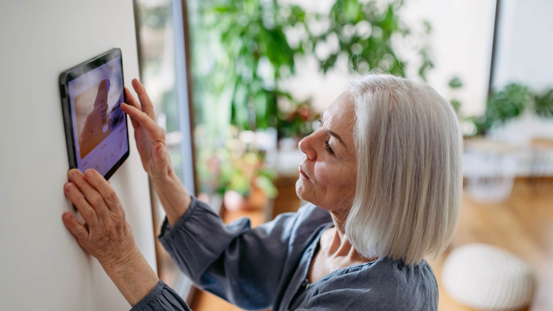 boomer woman changing the thermostat for comfort