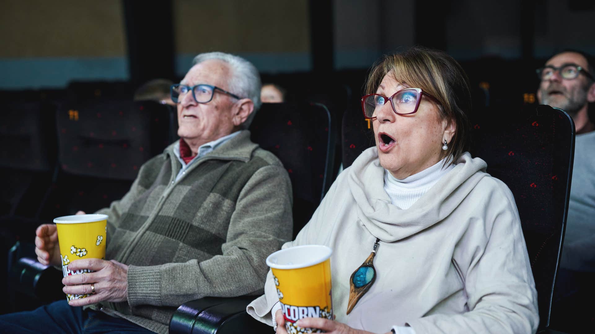 older couple holding popcorn in a movie theater