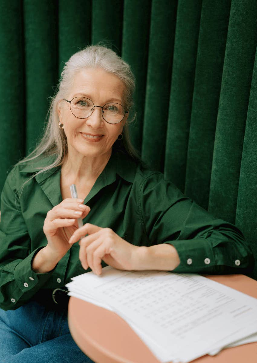 smiling older woman in glasses holding a pen