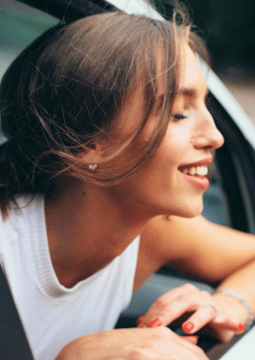 smiling woman leaning out of car