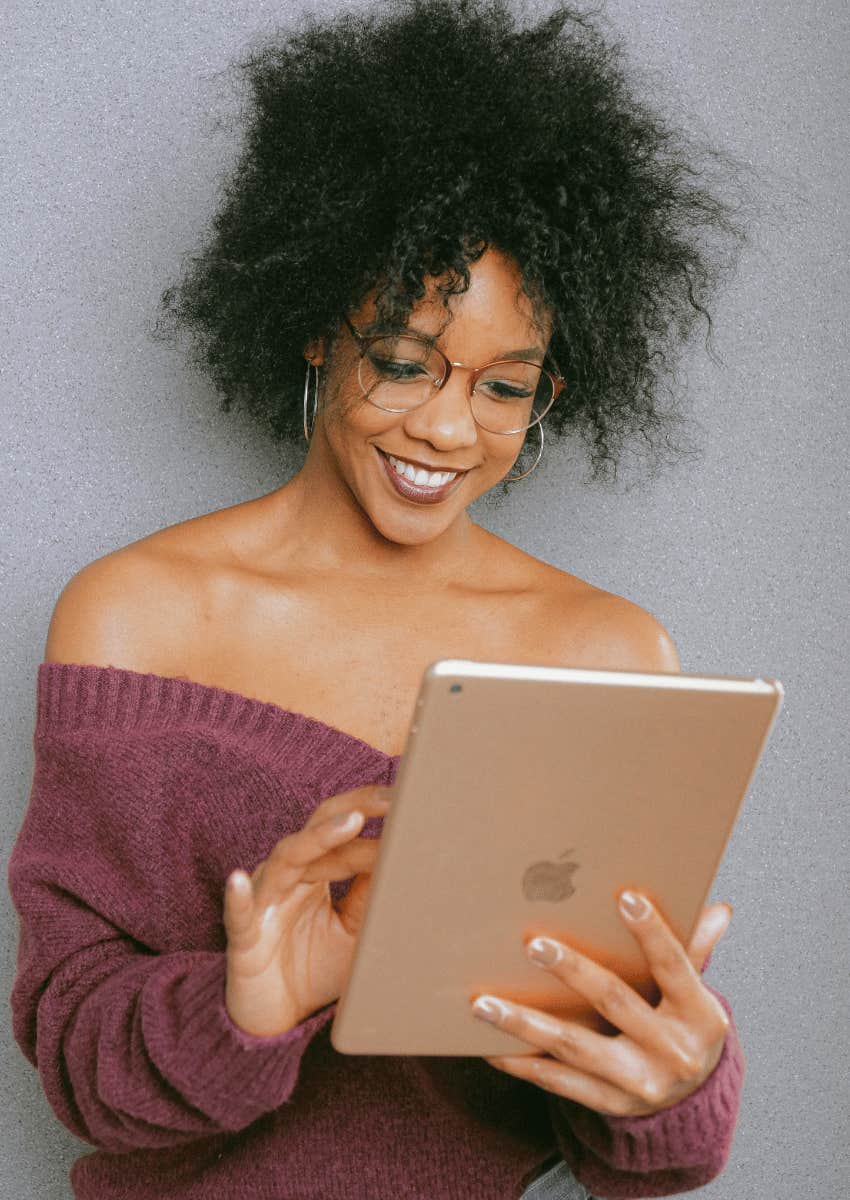 smiling woman looking down at an ipad screen