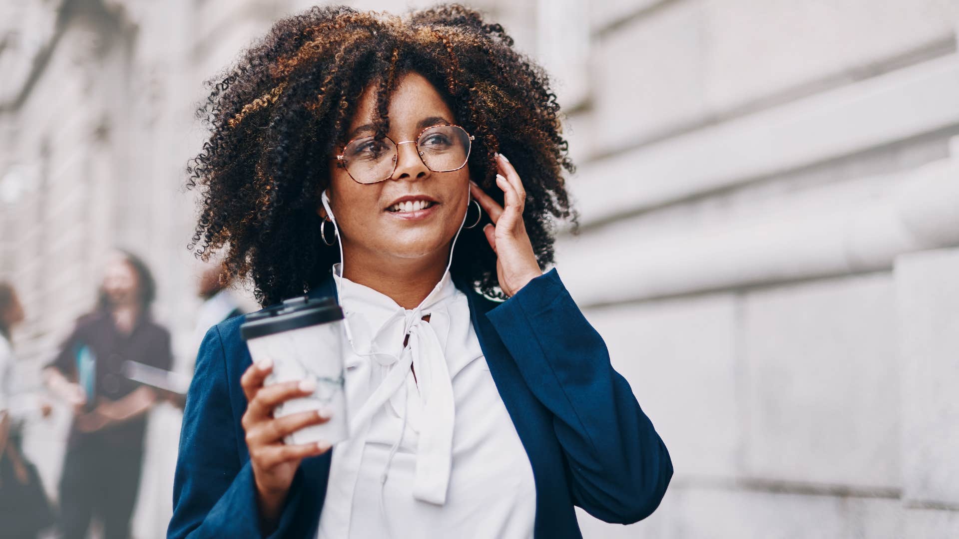 introverted woman walking outside with headphones on