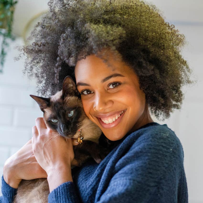 smiling woman posing with cat who is her soul pet 