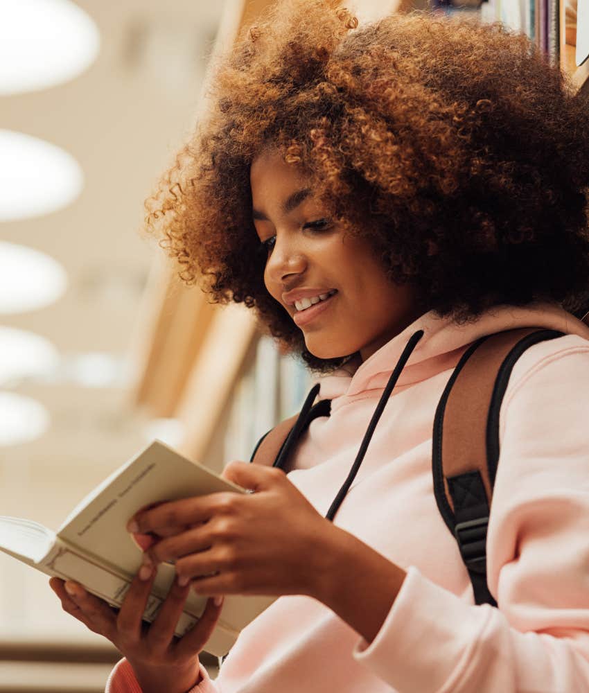 Young woman reading book because she is more likely to be offline