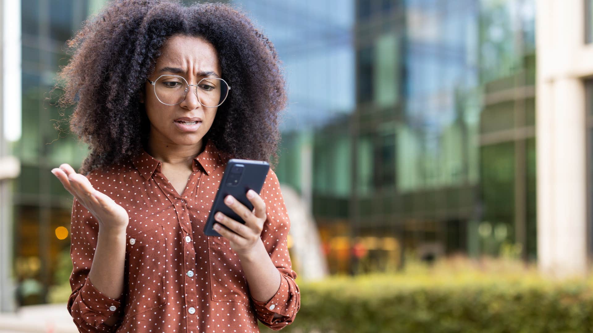 upset woman looking at her phone outside