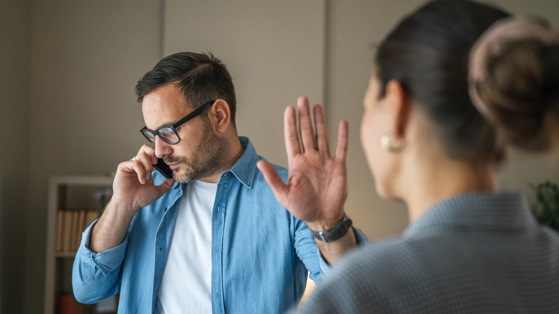 man in blue holding up hand as woman tries to interrupt him