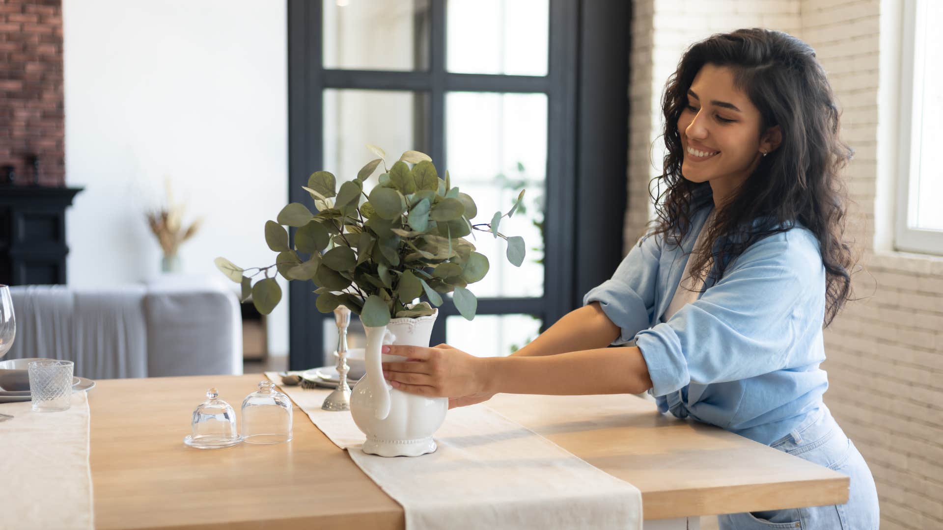 woman in blue shirt rearranging her living space frequently as she fixes table
