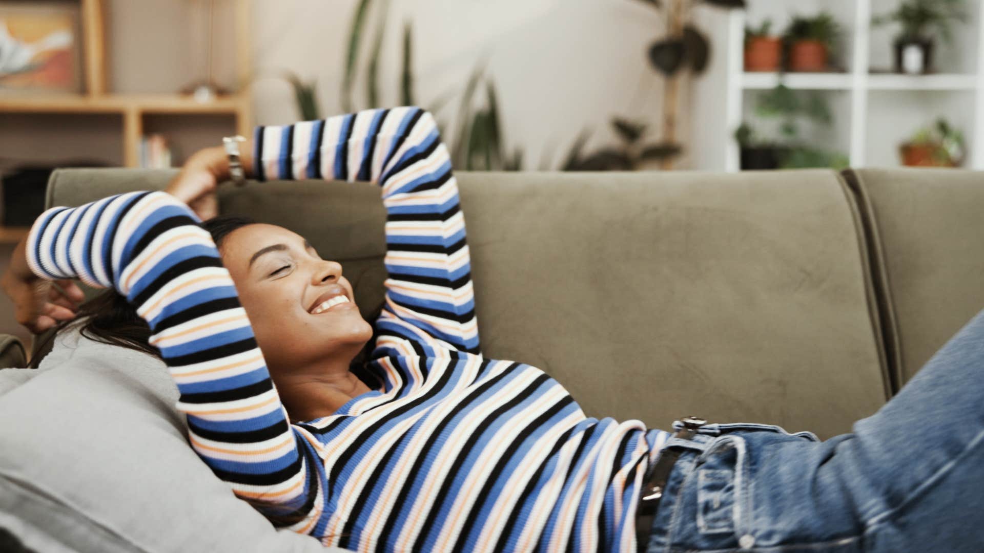 woman in stripped shirt relaxing on couch as she leaves a mess on purpose