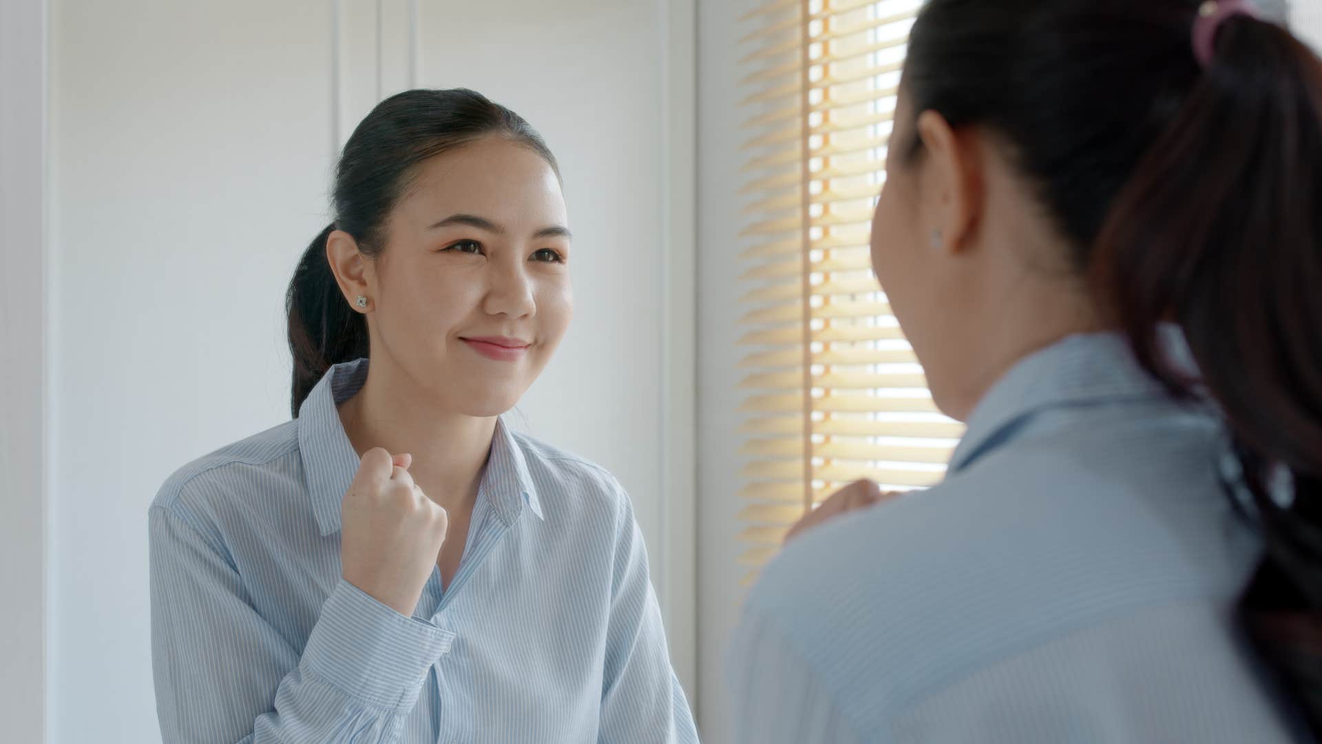 woman in blue shirt practices explaining ideas in front of mirror
